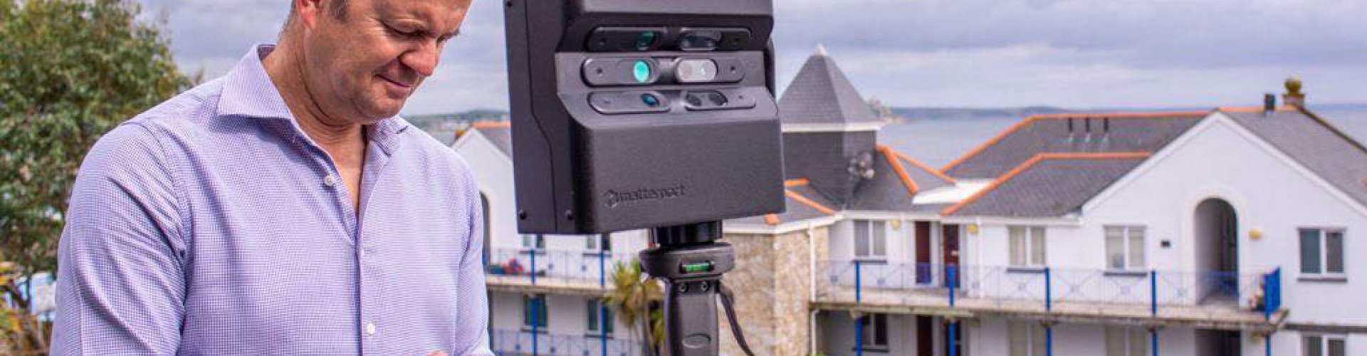 Man using 3d camera with houses in background