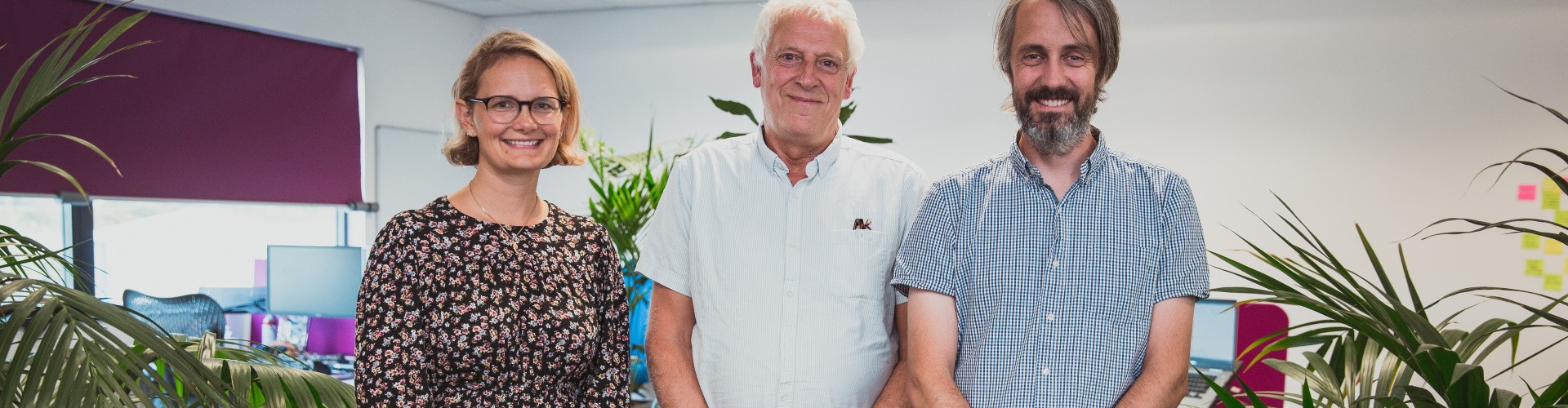 Three people in an office smiling at the camera 