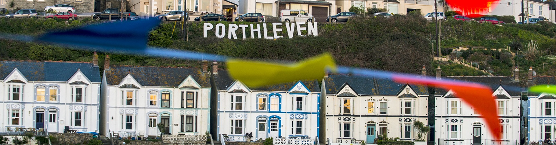 houses on Porthleven hill with sign and bunting at the food festival