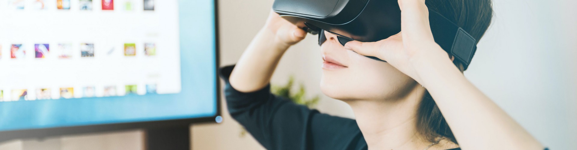 woman using virtual reality headset with computer in background