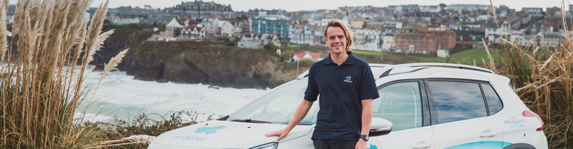 wildanet company car and employee with Cornish sea cliffs and town background