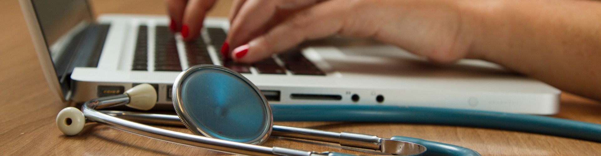 doctor typing at a laptop with stethoscope in foreground