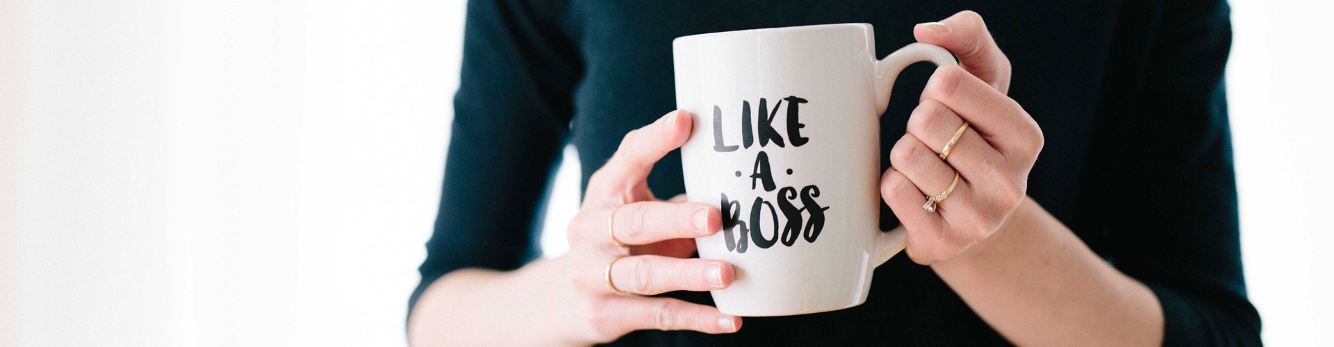 woman's hands holding mug with like a boss slogan