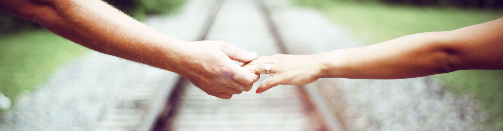 couple holding hands with railway in background