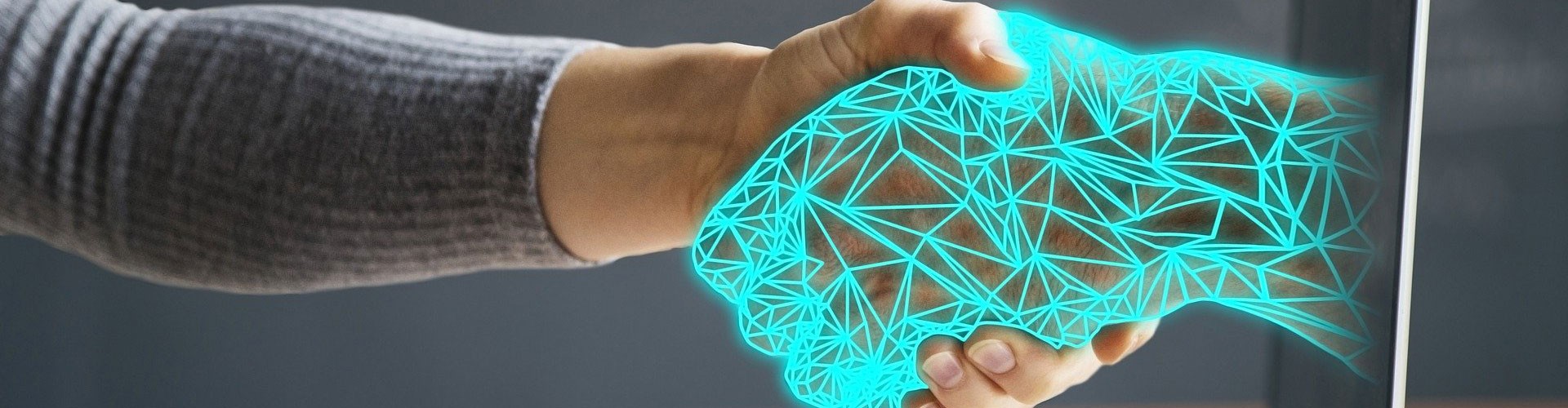 digital hand emerging from a laptop to shake real human hand