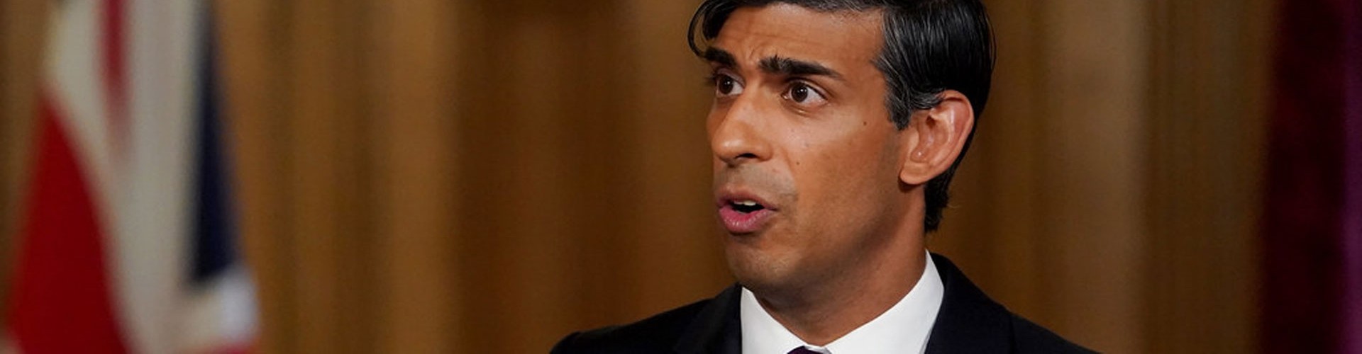rishi sunak giving a speech with union jack behind