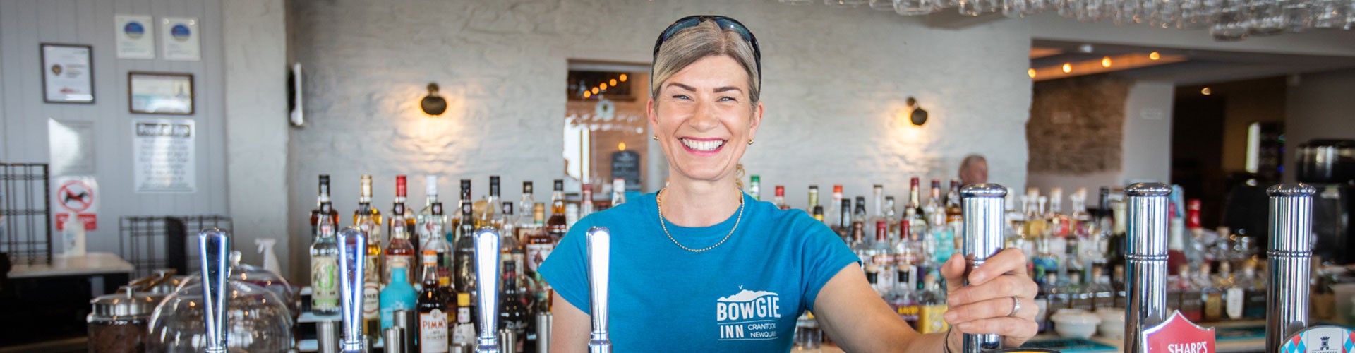 Owner of Bowgie Inn smiling behind the bar