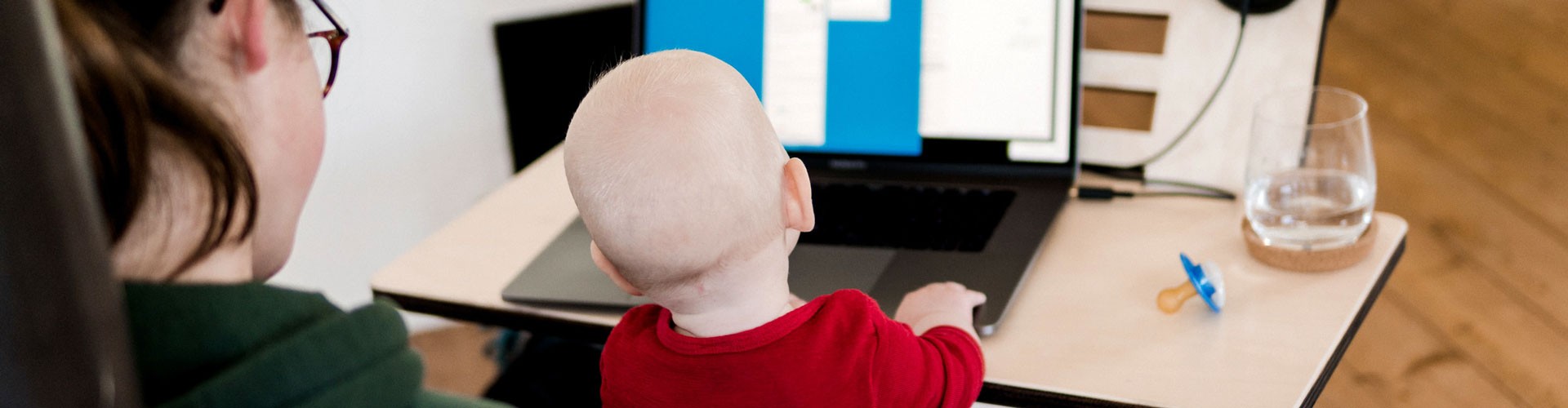 mother with baby sitting at laptop trying to work