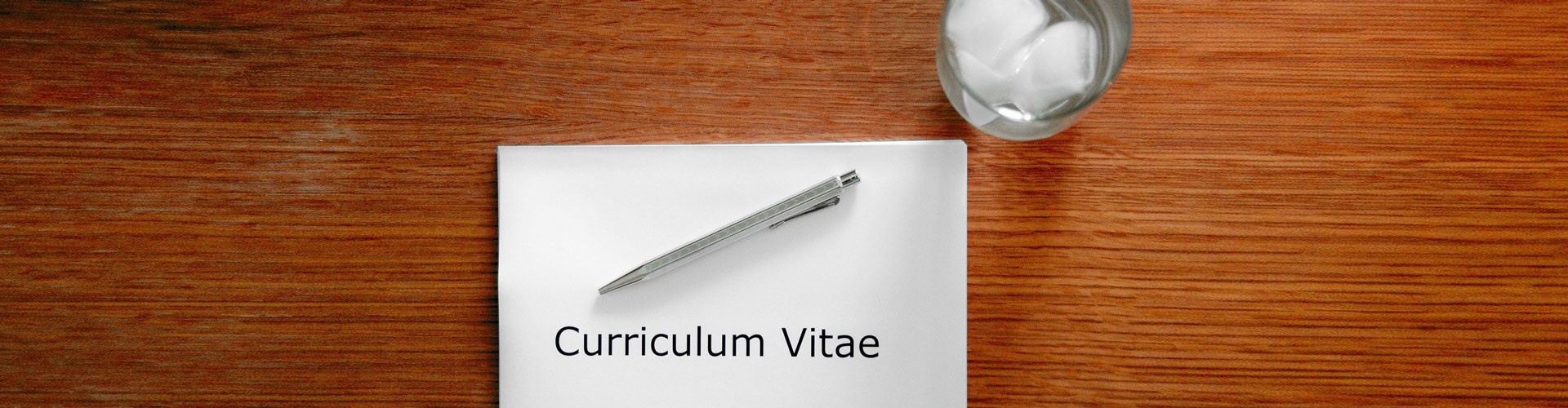 CV on wooden table with pen and glass of water