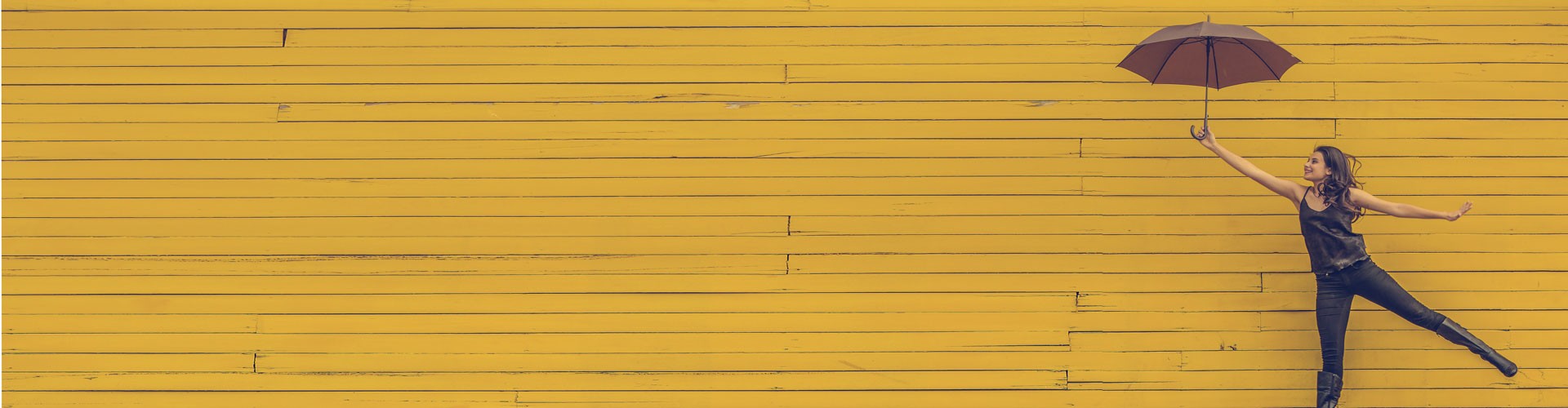 young woman holding umbrella against yellow background