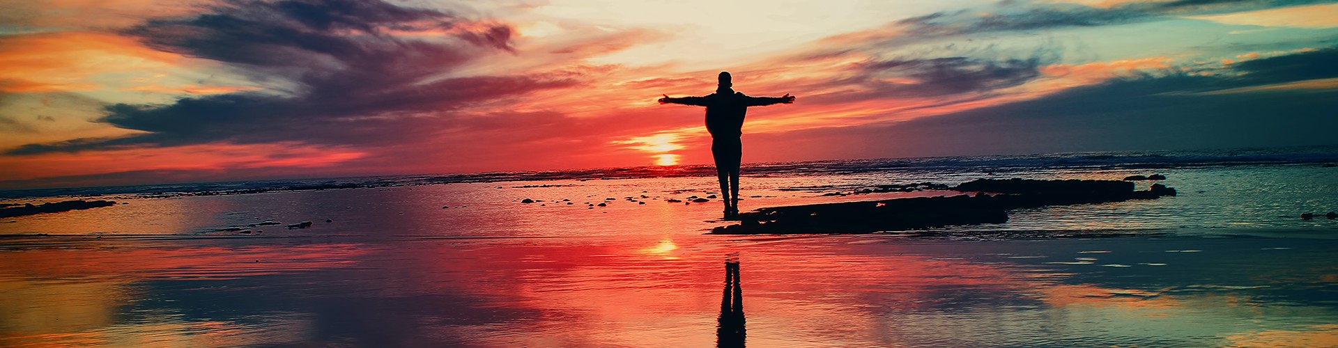 person standing on the beach at sunrise