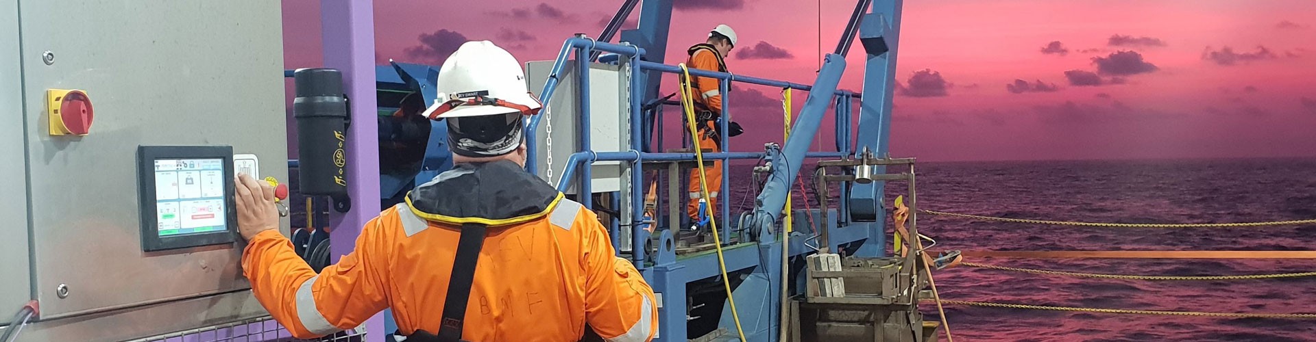 men working on a platform at sea with sunset in background
