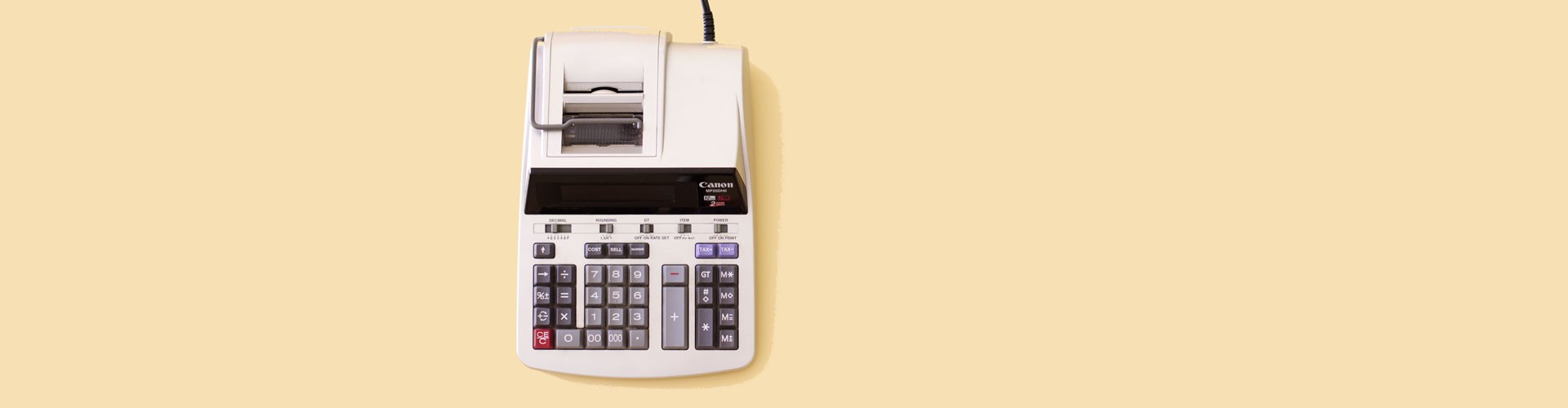 old fashioned calculator on pale yellow background