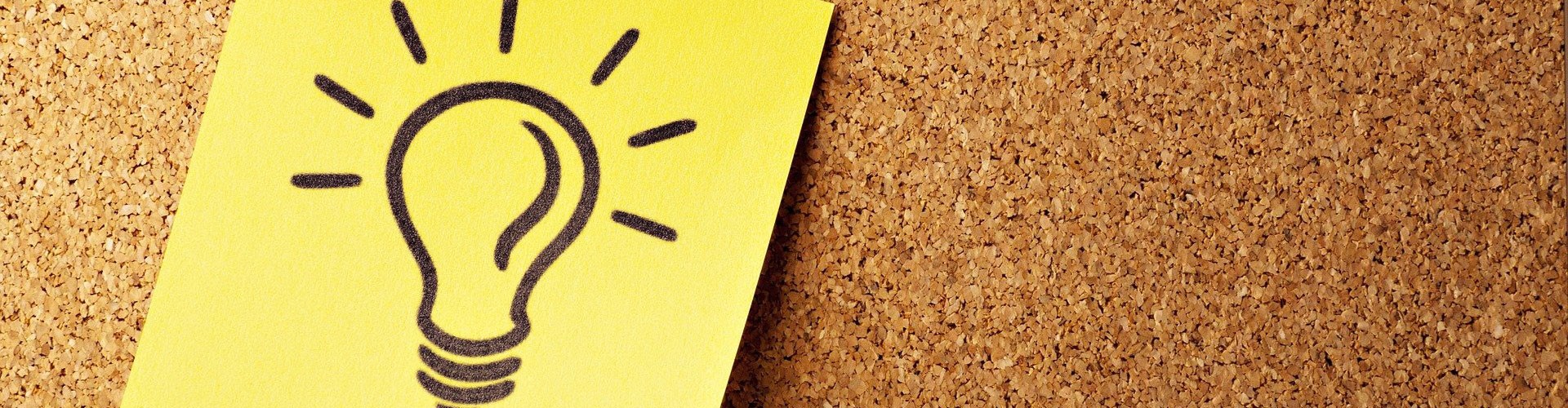 postit not with a drawing of a lightbulb pinned to a cork-board
