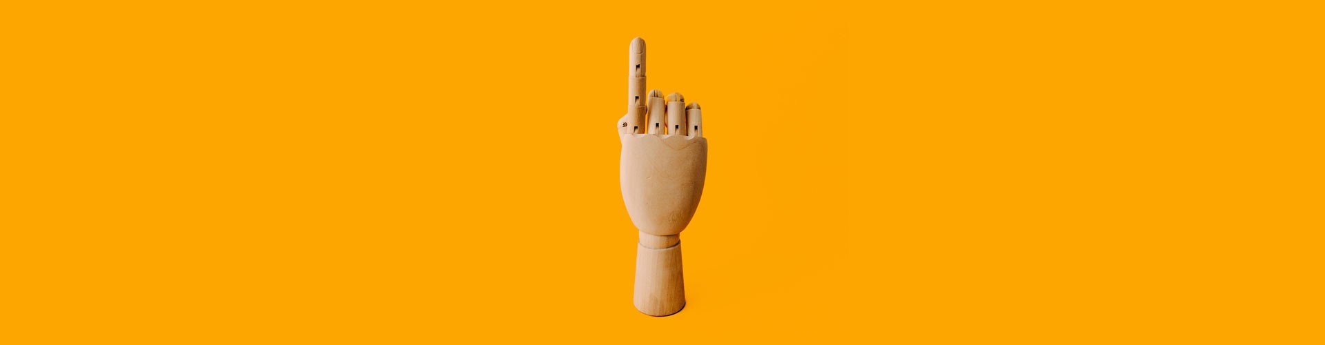 wooden hand pointing up on rich yellow background