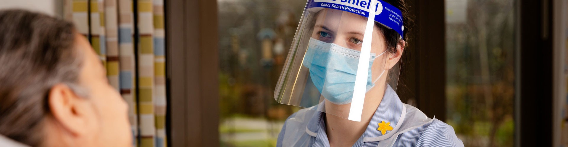 Marie Curie nurse wearing PPE at a patient's bedside
