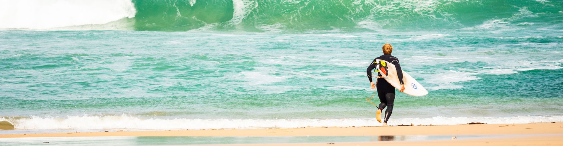 green waves with surfer running into sea
