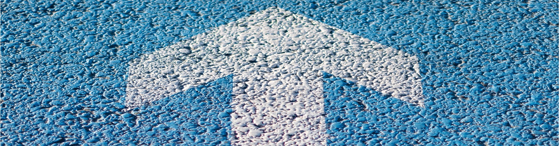 white arrow painted on blue tarmac background