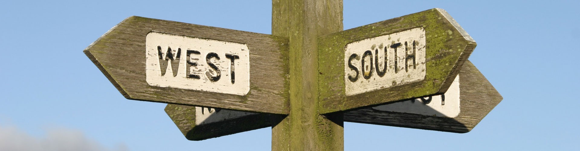 wooden signpost showing west and south