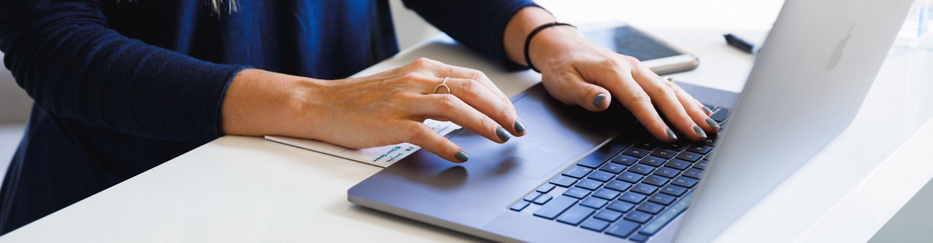 woman's hands typing at a laptop