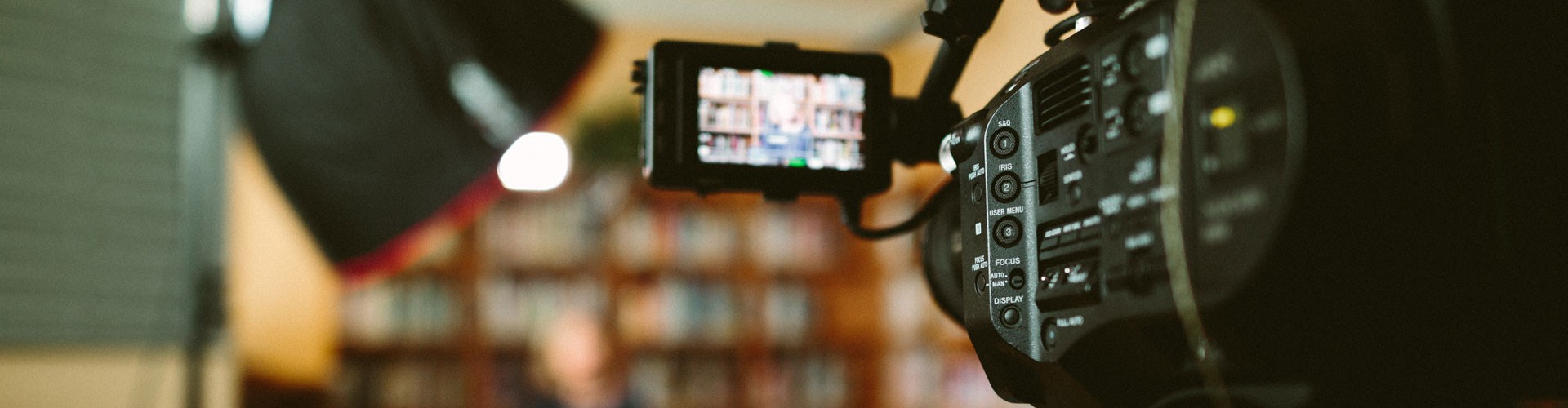 film camera filming a lady in front of a book case