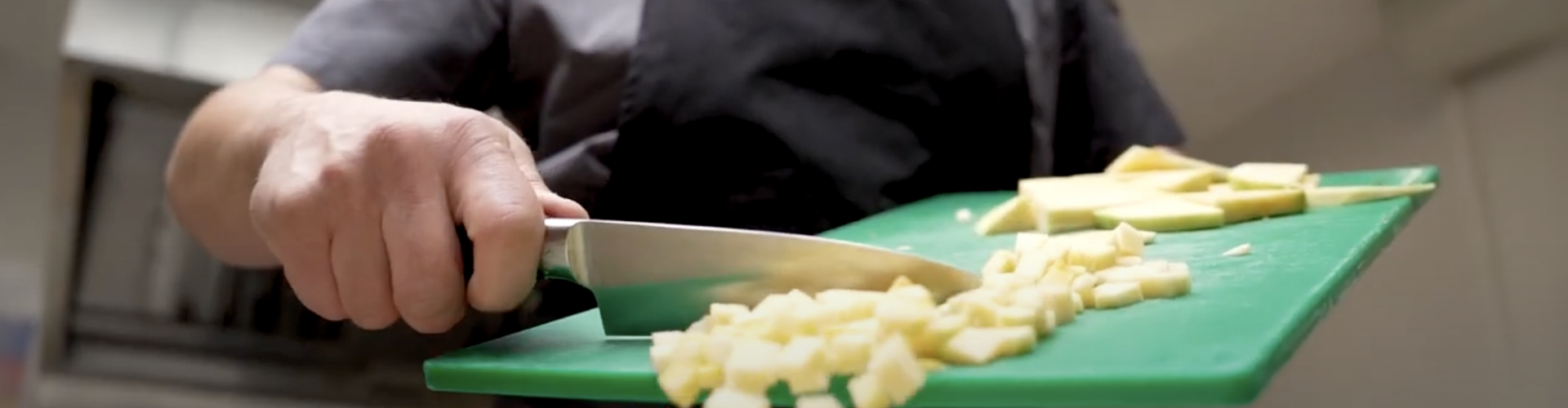 Someone using a knife to chop vegetables
