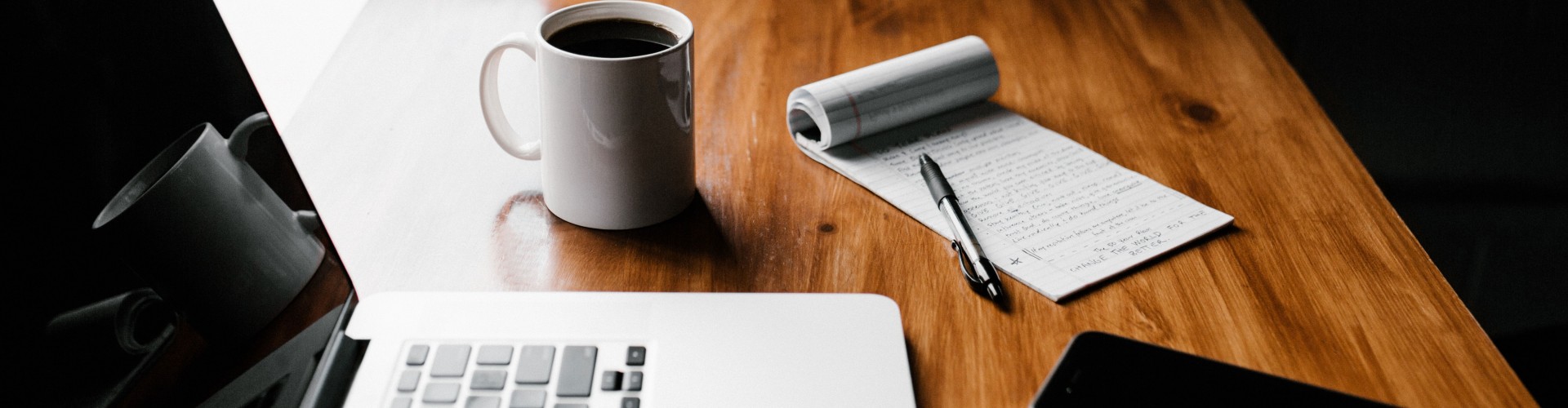 A laptop, writing paper, pen and coffee