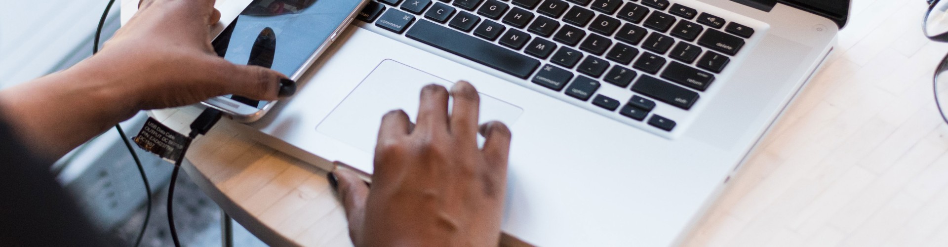 A person's hands by laptop and phone