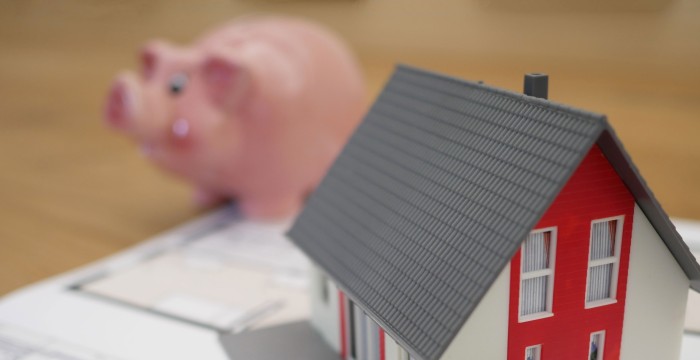 A toy house in front of a pig money bank