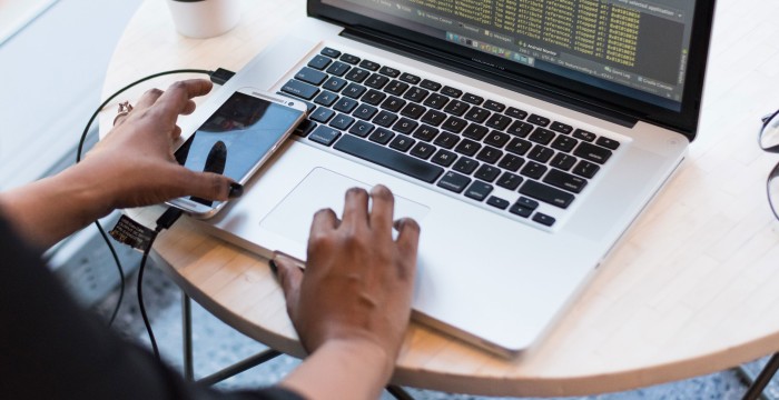 A person's hands by laptop and phone