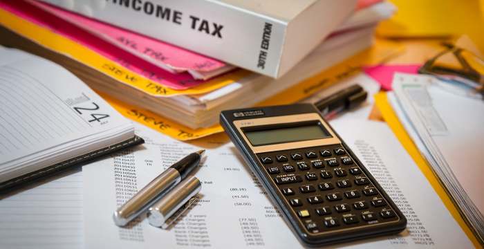 pile of papers with calulator for income tax