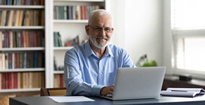 older man sitting at laptop looking happy