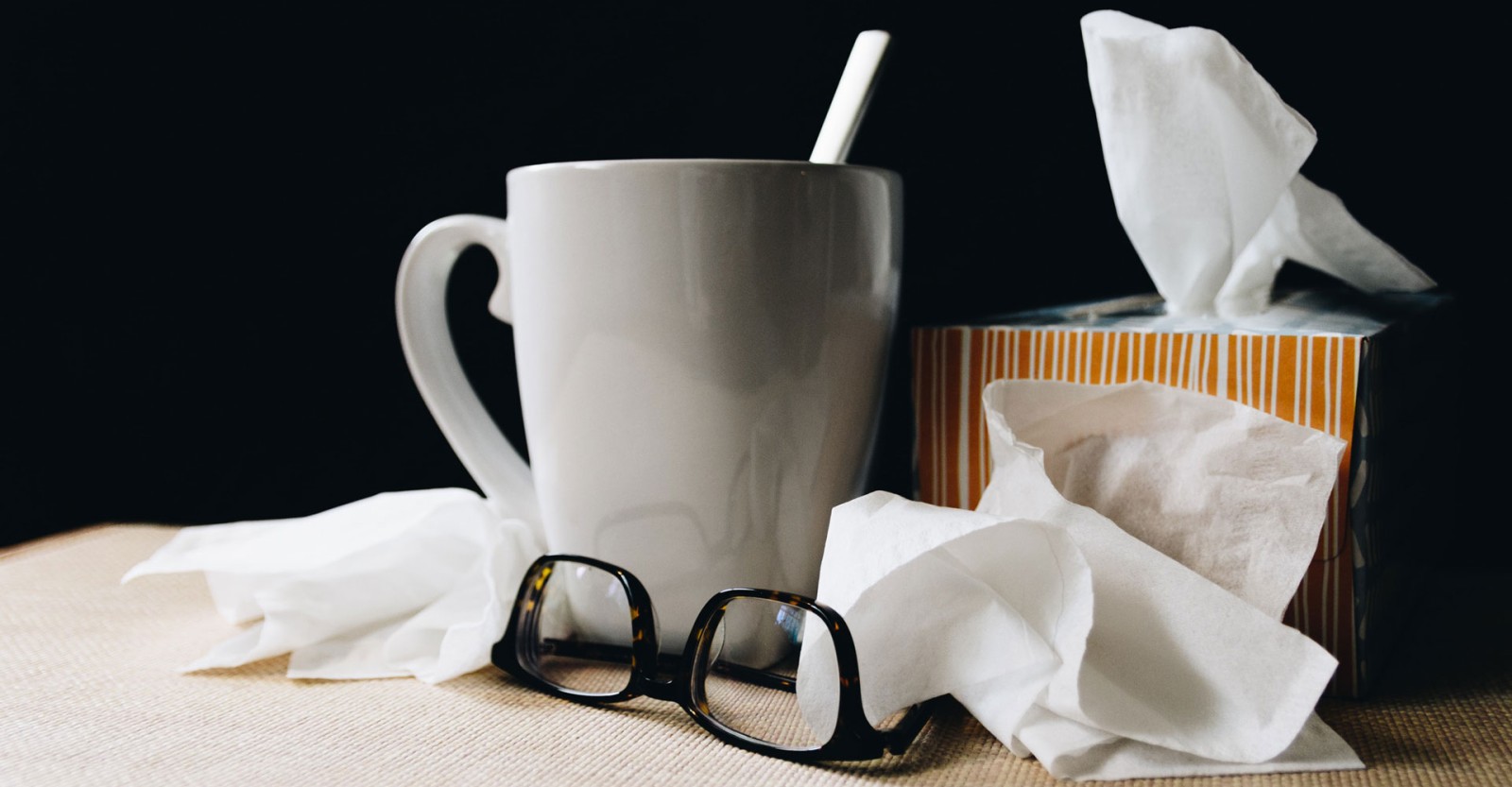 used tissues, hot drink and glasses suggesting a cold or flu