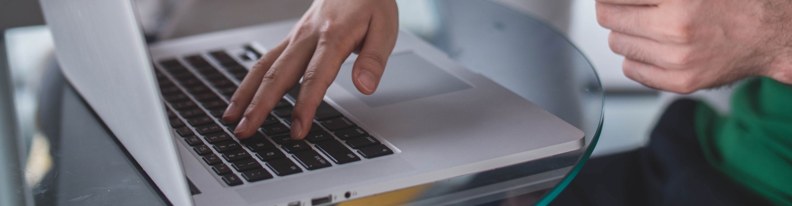 Hands and a laptop on a glass table