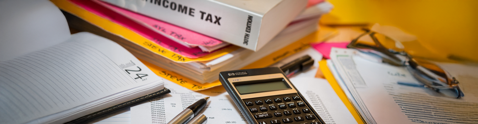 pile of papers with calulator for income tax