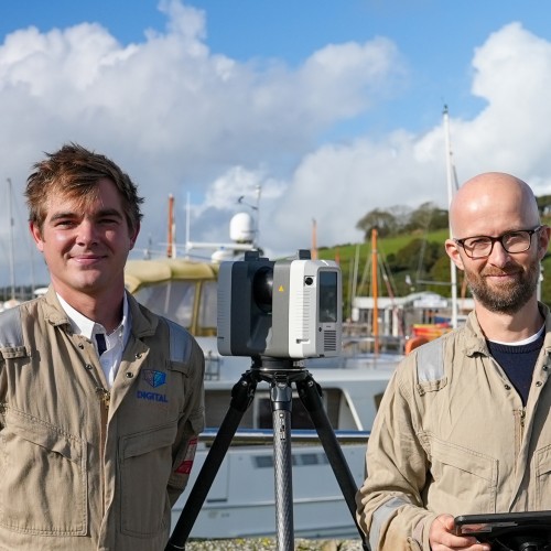 Two people in the sunshine with tech on a stand between them